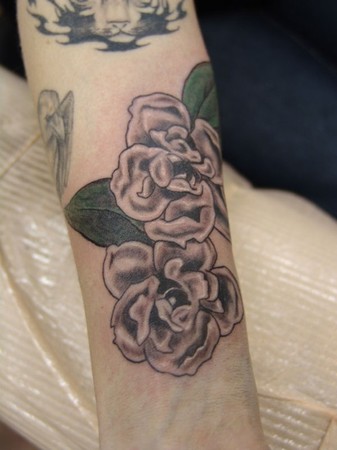 Simple black and grey tattoo of magnolias using a washed down green in the 