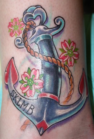 a tattoo of a small pink heart on her little finger and an anchor under