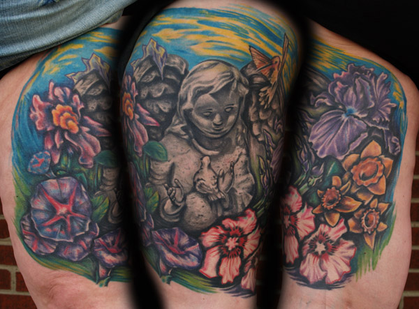 Statue and flowers memorial. Placement: Leg Comments: This is a tattoo to remember her mother. She wanted a black and gray statue with colorful flowers from 