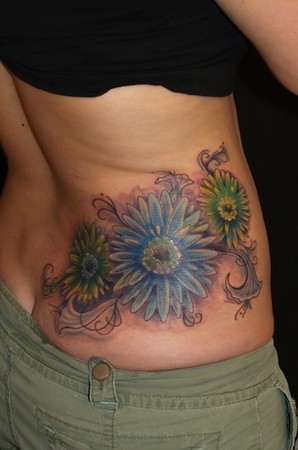 flowers with filigree accents on side of back tattoo